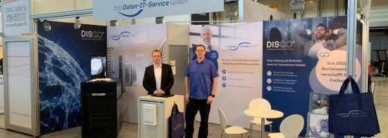 Zwei Männer die im Messestand von DIS Daten-IT-Service stehen.